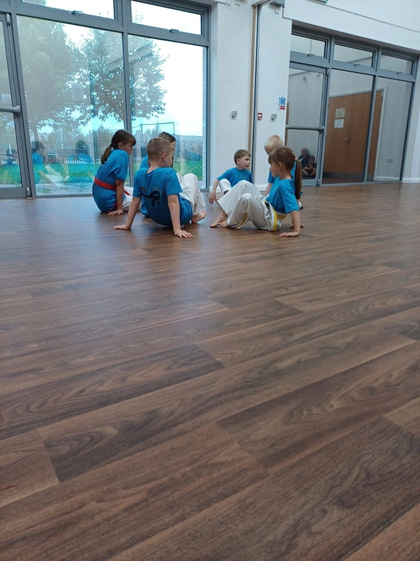 Group of children on the floor in a circle performing drills